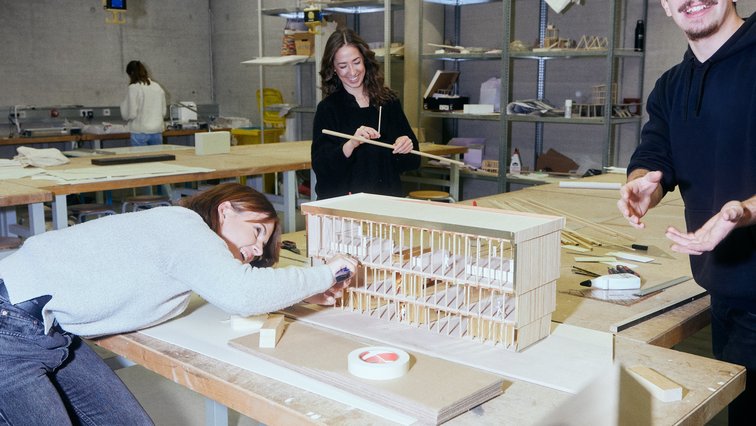 Three students are building an architectural model