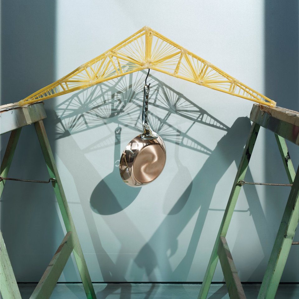 Darstellung einer Brücke aus Spaghetti, an der ein Topf hängt