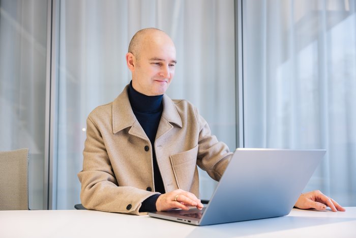 Professor blickt am Arbeitsplatz auf Laptop
