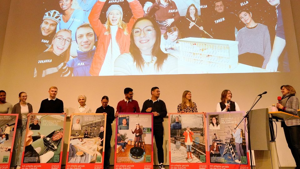 Studierende mit Postern auf einer Bühne